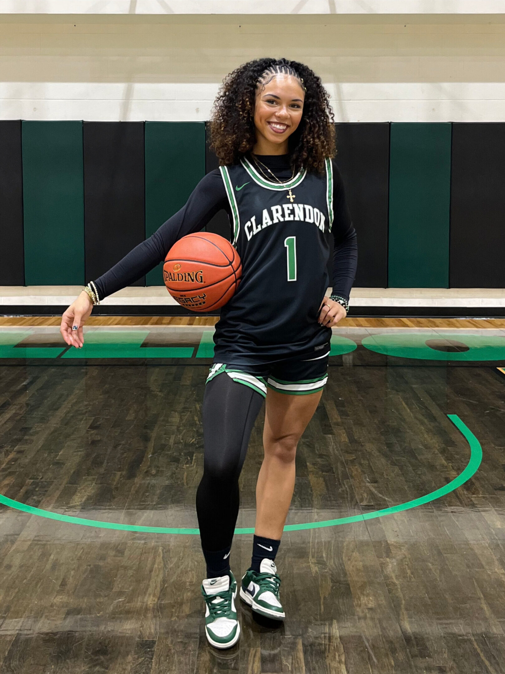 Female basketball player posing with ball on court.