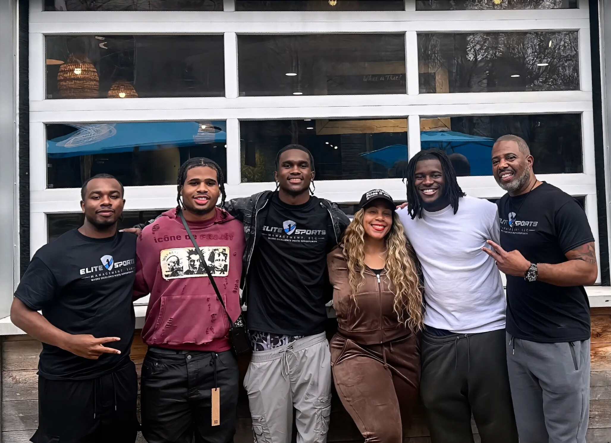 A group of six friends posing happily in front of a garage door.