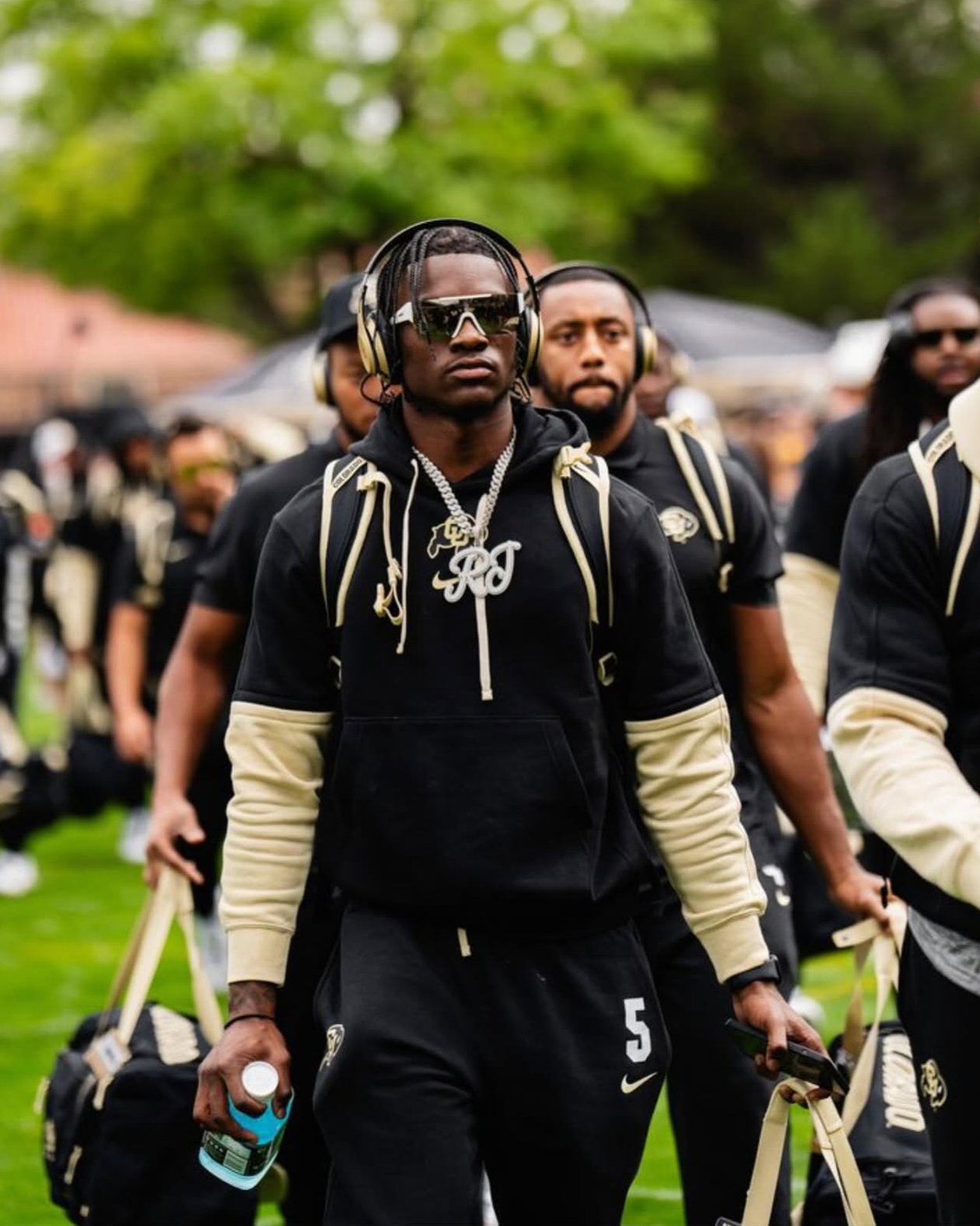Athletes walking together in black sportswear and headphones.